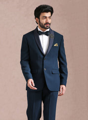 A teal suit with embroidered motif, designer wear.
